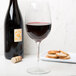 A Reserve by Libbey Renaissance wine glass filled with red wine next to a bottle and crackers.