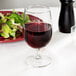 A Libbey Vina goblet of red wine next to a plate of salad.
