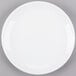 A Libbey Porcelana bright white round porcelain coupe plate on a gray surface.