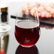 A Reserve by Libbey Renaissance stemless wine glass filled with red wine sits on a table.