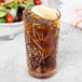 A Libbey Hobstar cooler glass of iced tea with a lemon wedge in it on a table.