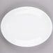 A Libbey Porcelana white oval coupe platter with a white rim on a gray surface.