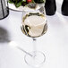 A Reserve by Libbey Prism wine glass filled with white wine on a table.