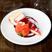 A slice of cheesecake with strawberries on a Libbey Porcelana round white coupe plate.