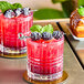 Two glasses of red drinks with blackberries on the rim.