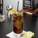 A Reserve by Libbey Modernist beverage glass of ice tea with a lime slice on a napkin.