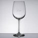 A Libbey Vina wine glass with etched "Vino!" decoration on a table.