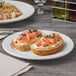 A Libbey Porcelana bright white porcelain plate with food on a table.