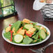 A Libbey Porcelana round coupe plate with a salad with croutons, cucumbers, and green peppers.