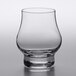 A close-up of a clear Libbey Reserve Distill Whiskey Glass with a small amount of liquid in it.