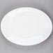 A Libbey Porcelana Bright White oval platter with a white rim on a gray surface.