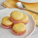 A white plate with three yellow macarons on it.