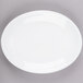 A Libbey bright white oval coupe platter with a white rim on a gray surface.