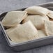 A metal container filled with unbaked Caribbean Food Delights vegetable patties.