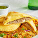 A plate with rice and a Caribbean Food Delights Unbaked Jerk Chicken Patty.