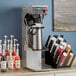 A Curtis coffee and tea brewer on a shelf with a variety of drinks.