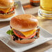 A hamburger served on a Turano frozen hamburger bun with lettuce, tomato, cheddar cheese, and a beef patty.