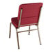 A Lancaster Table & Seating church chair with burgundy fabric and gold metal legs.