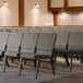 Lancaster Table & Seating church chairs in a row with gray fabric seats.