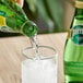 A person pouring Perrier Sparkling water from a green glass bottle into a glass.