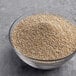 A bowl of white quinoa seeds on a gray surface.