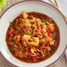 A bowl of Lee Kum Kee Chili Bean Sauce on a table with cabbage and meat.