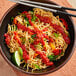 A bowl of noodles with Lee Kum Kee chili garlic sauce and vegetables on a white background.