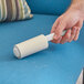 A hand using a 3M Scotch-Brite Greener Clean lint roller to clean a couch.