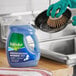 A gloved hand uses Palmolive Oxy Power Degreaser to clean a pot.