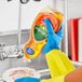 A person in yellow gloves pouring Palmolive dish soap from a plastic bottle into a bowl.