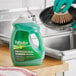 A person wearing a glove using Palmolive Ultra Professional Original Scent dishwashing liquid to wash a pan.