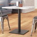 A table with a marble top and a black Lancaster Table & Seating steel table base.