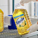 A person in gloves holding a plastic bottle of yellow Fabuloso multi-purpose cleaner.
