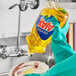 A person in gloves pouring Ajax Lemon Scent dish soap into a bowl.