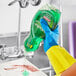A person in yellow gloves pouring Palmolive dish soap from a bottle.