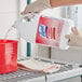 A person pouring Professional Lysol sanitizer into a red container.