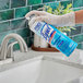 A person in gloves spraying a bathroom sink with Professional Lysol Disinfectant Spray.