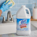 A person wearing blue gloves using Professional Lysol Disinfectant Heavy-Duty Bathroom Cleaner to clean a bathroom sink.