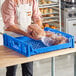 A man in an apron holding a bag of bread in a blue Baker's Lane bread tray.