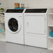 A white Speed Queen front load gas dryer in a laundry room.