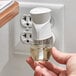 A hand holding an Air Wick Fresh Waters scented oil refill over a wall outlet.