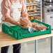 A man in an apron holding a bag of bread in a green Baker's Lane bread tray.