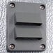 A grey metal rectangular wall plate with metal corners and two holes.