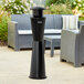 A black Lavex steel freestanding cigarette receptacle on an outdoor patio table.