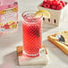 A glass of pink Twinings Raspberry & Lemon tea with ice and a lemon slice.