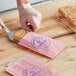 A person putting a cake in a customizable pink paper bag.