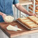 A person in a blue shirt using Henry & Henry Redi-Pak Cream Cheese Pastry Filling to prepare pastries.