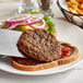 A plate with a knife and fork and a close-up of an AdvancePierre Pub Burger Patty served on it.