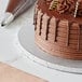 A chocolate cake on a Baker's Lane silver cake drum on a table in a bakery display.