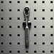 A Triton stainless steel spring clip holding a wrench on a metal surface.